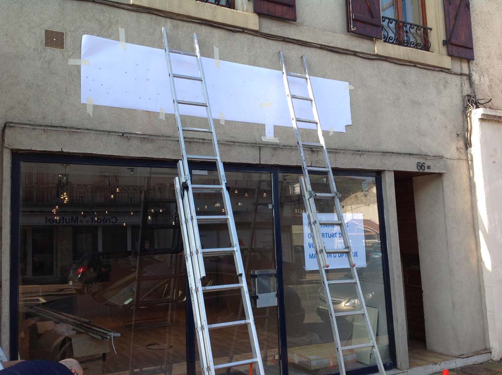 Positionnement du plan de pose pour la fixation des lettres en dibond sur la façade du magasin Salines Optic à Dombasles 54